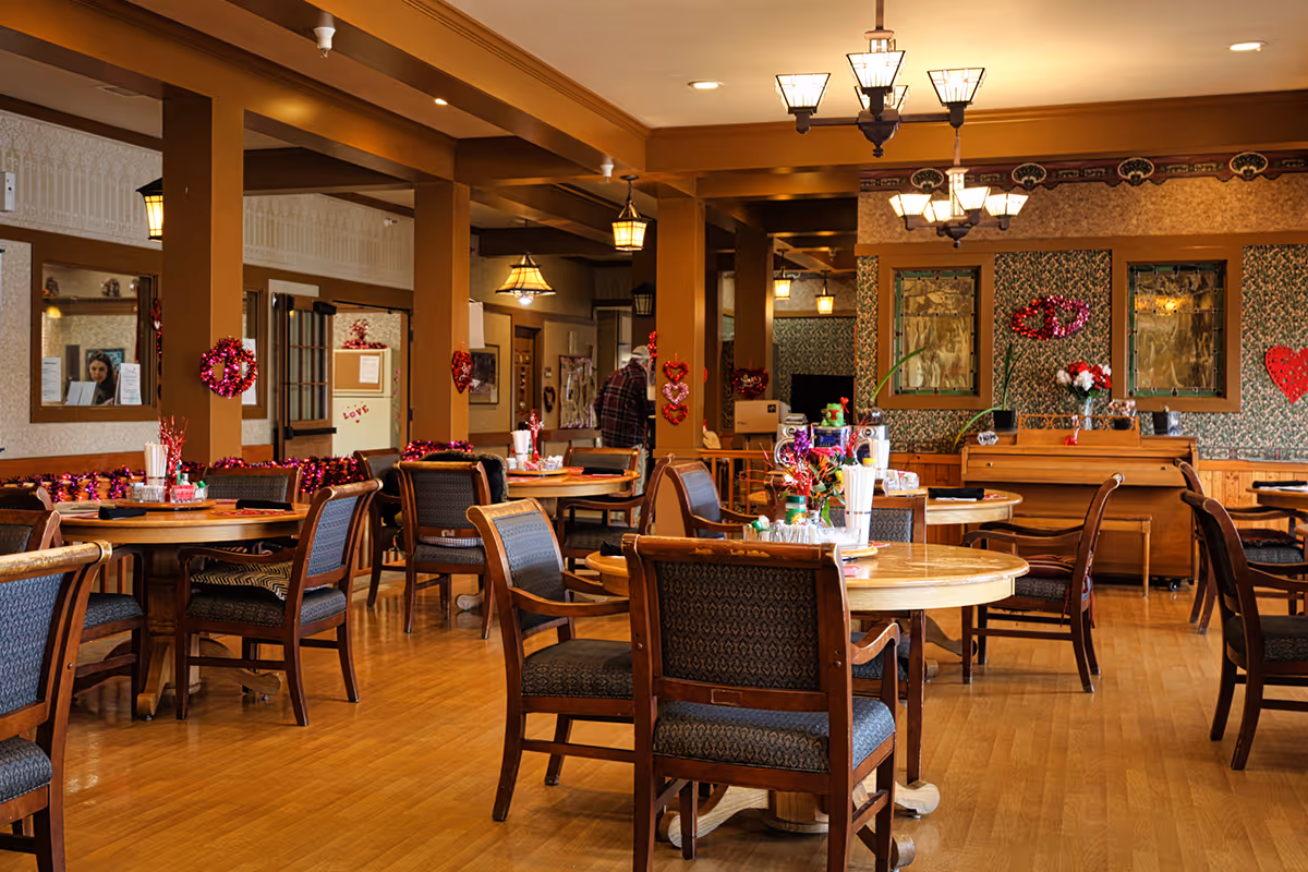 Communal dining room with round wooden tables and upholstered chairs decorated for Valentine's Day.
