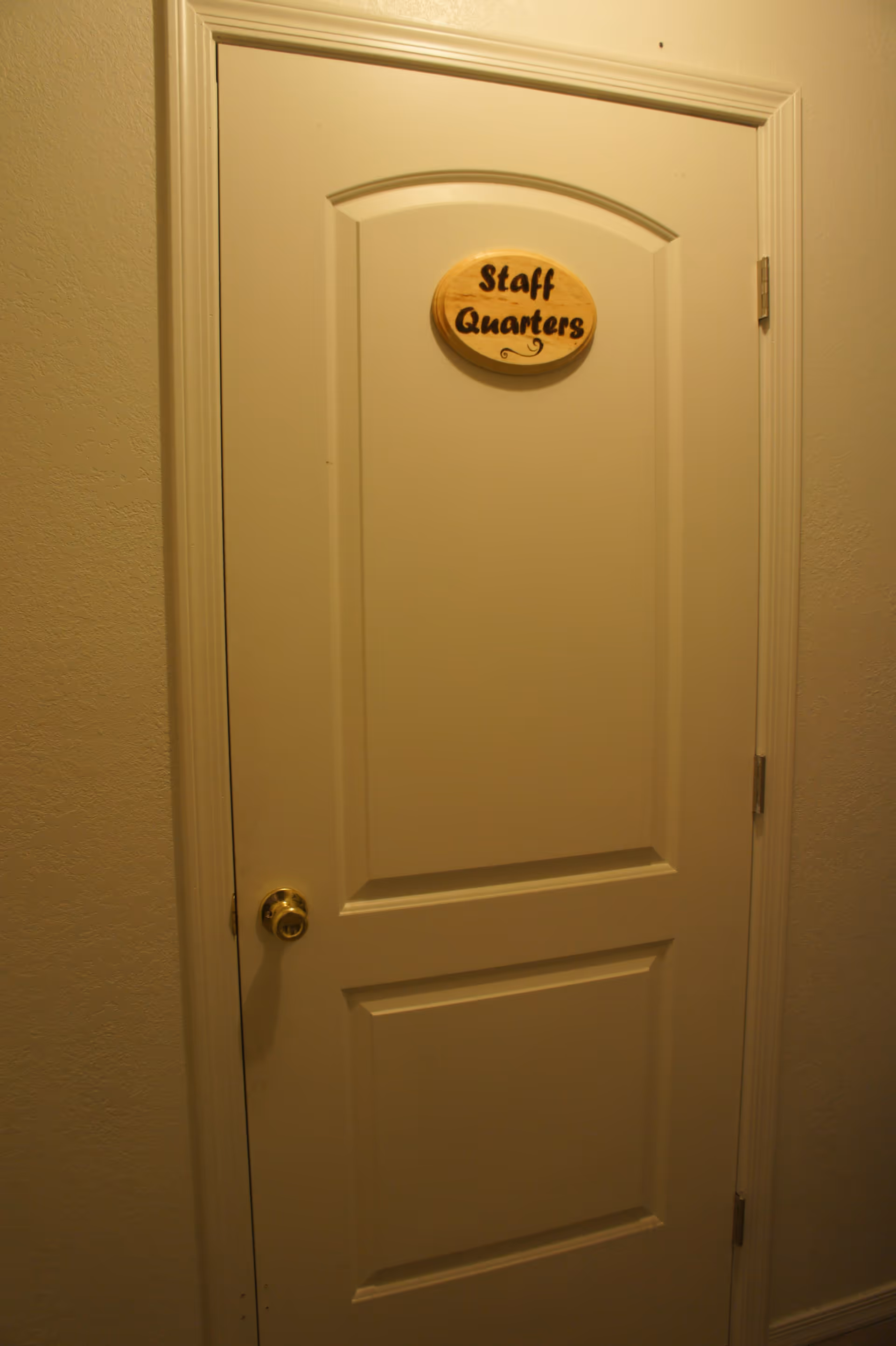 Closed interior door with an oval wooden sign reading "Staff Quarters".