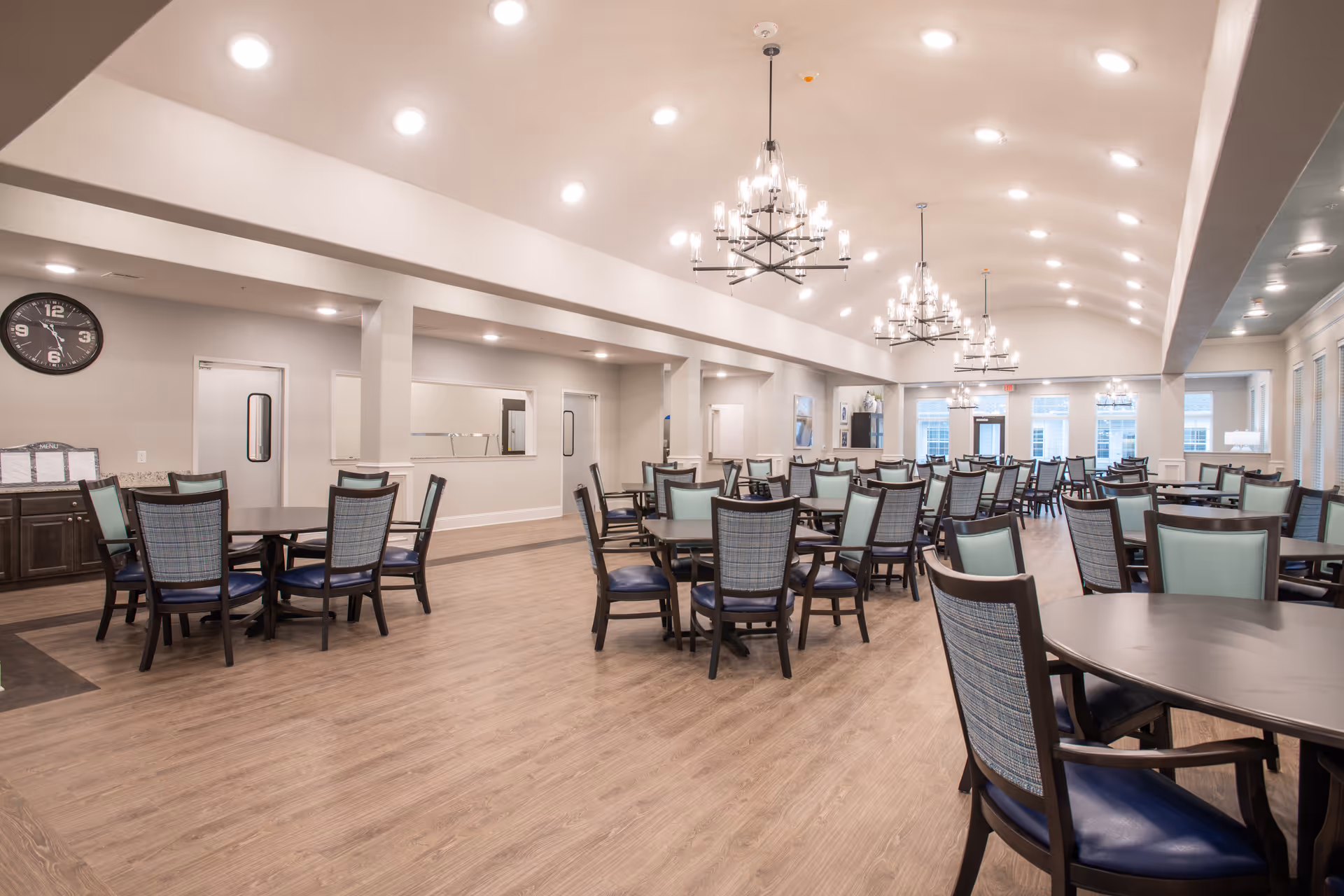 Spacious dining room with multiple round tables and chairs under chandeliers.