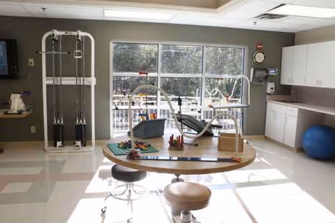 Therapy room inside Oak Park Nursing and Rehabilitation Center with exercise machines and a round table.