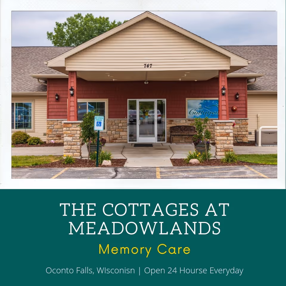 Front entrance of The Cottages at Meadowlands memory care building with a covered portico, stone pillars, and glass double doors.