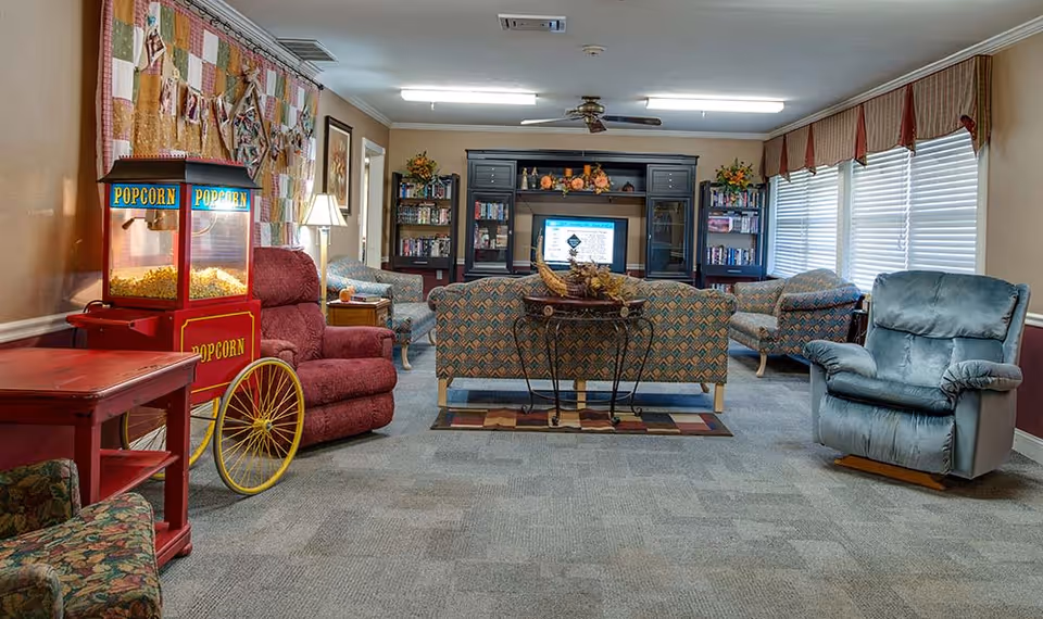 Comfortable communal living room with sofas, recliners, a popcorn cart, and an entertainment center with a TV.