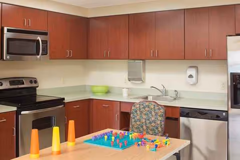 Kitchen area with wooden cabinets, stainless steel appliances, and a game table.