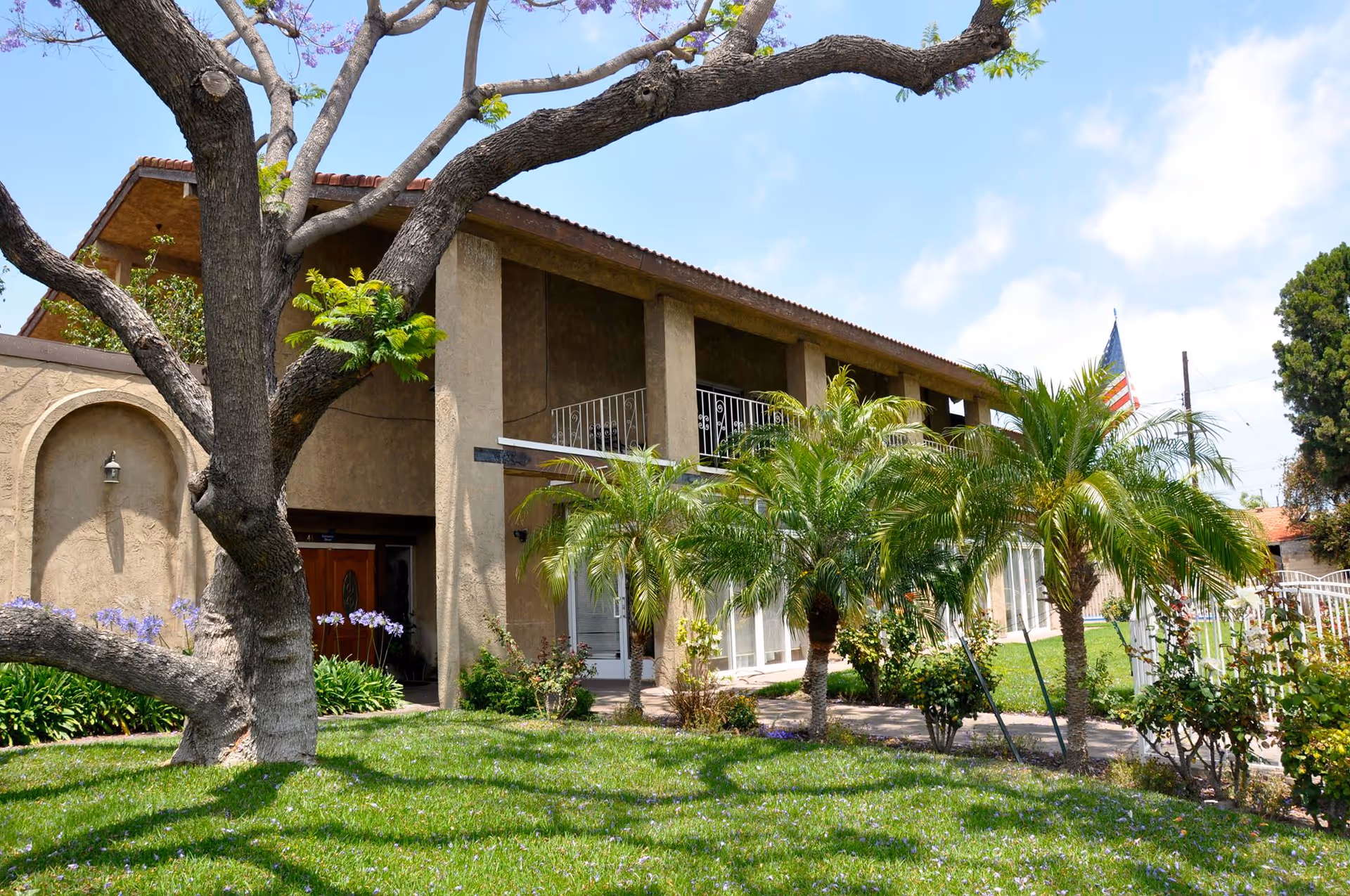 Exterior view of New Horizon Senior Living building with lawn and palm trees.