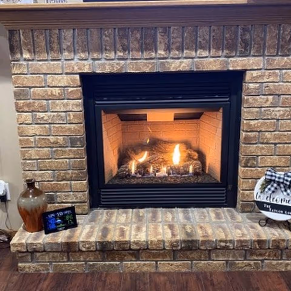 Brick fireplace with a burning gas fire and decorative items on the hearth.