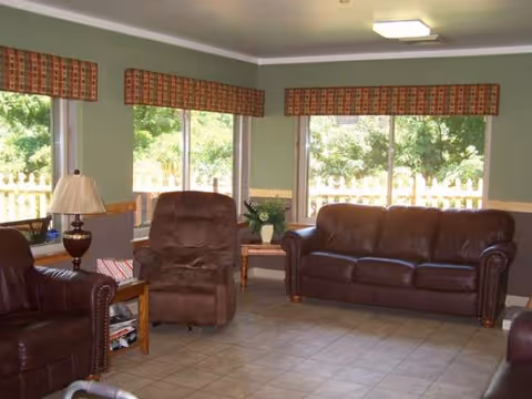 Cozy living room with leather furniture, large windows, and tiled floor.