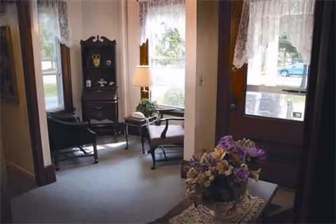 Cozy living room in Prospect Place with chairs, a lamp, and a flower arrangement