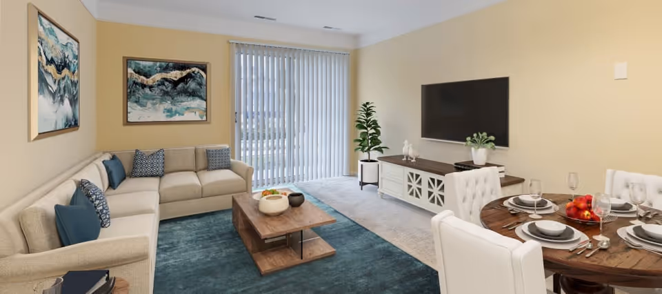 Bright open living room and dining area with a sectional sofa, coffee table, wall-mounted TV, and a set dining table.