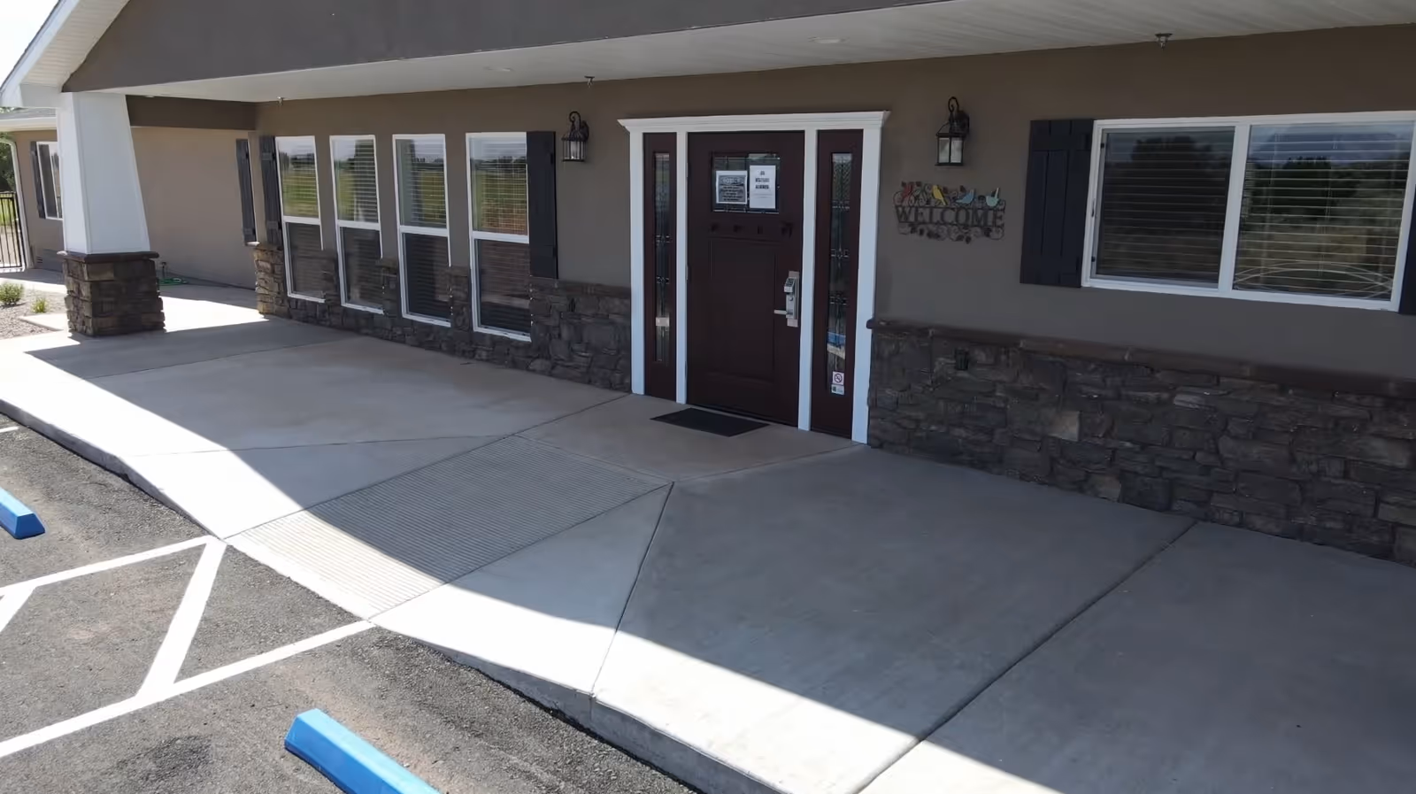 Exterior view of BeeHive Homes entrance with sidewalk and stone facade.