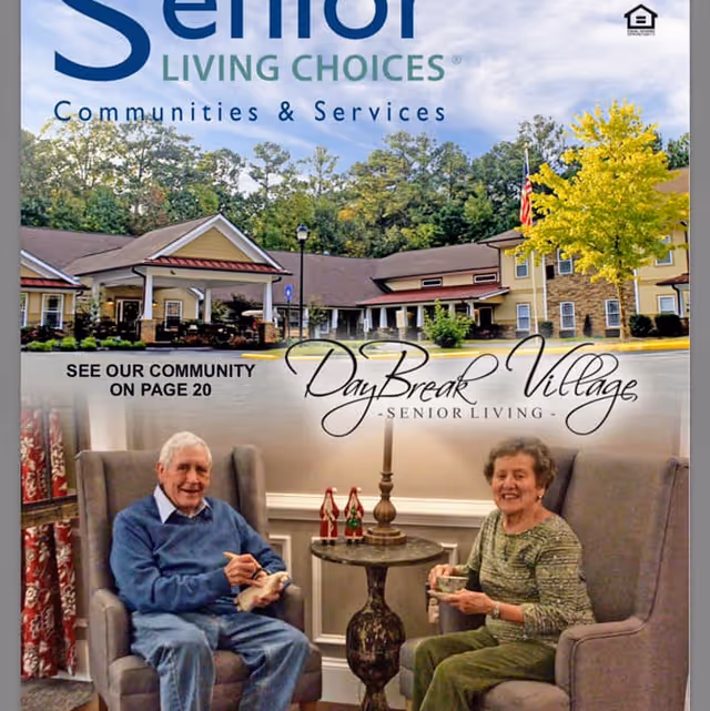 Two elderly people sitting in comfortable armchairs in a cozy living room area, smiling and holding cups. Behind them is a small round table with decorative items and a lamp. Above them is an image of the exterior of a senior living community building surrounded by trees and a clear sky. Text on the image includes 'Senior Living Choices Communities & Services' and 'DayBreak Village Senior Living'.