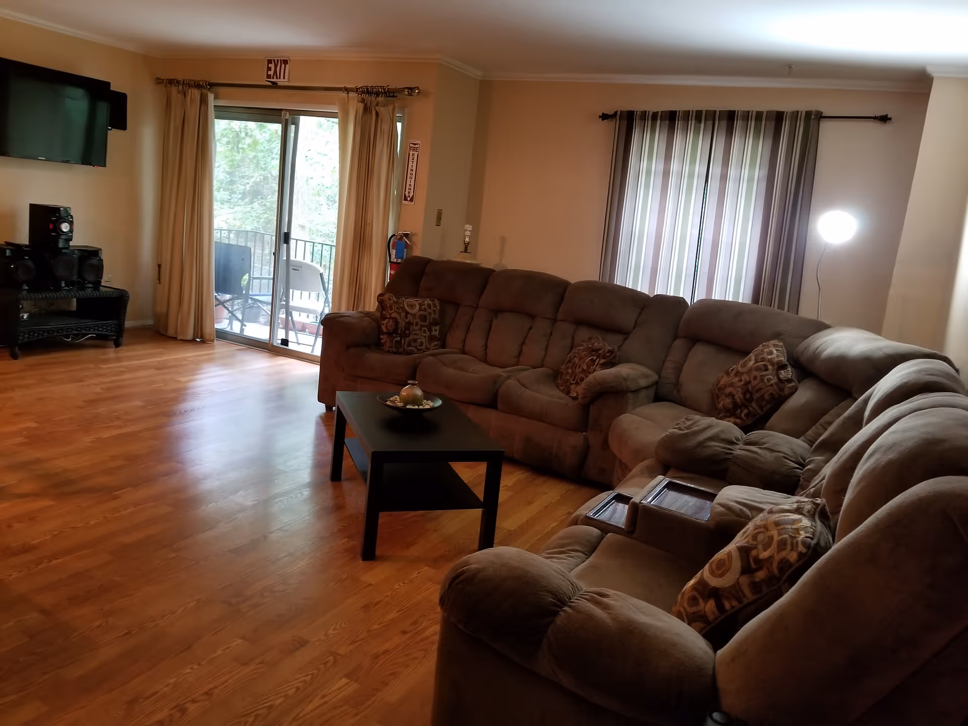 Spacious living room with a large sectional sofa, coffee table, TV, and sliding glass door to a balcony.