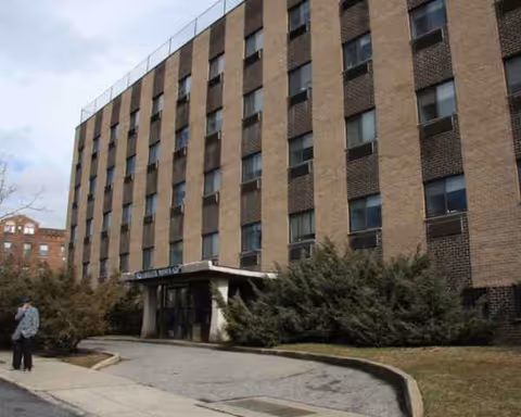 Exterior view of a multi-story brick senior living facility with an entrance canopy.
