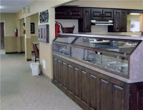 A long wooden service counter with a glass display in a senior facility dining area.