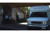 A Granbury Care Center shuttle van parked under the facility's covered entrance with people near the doorway.
