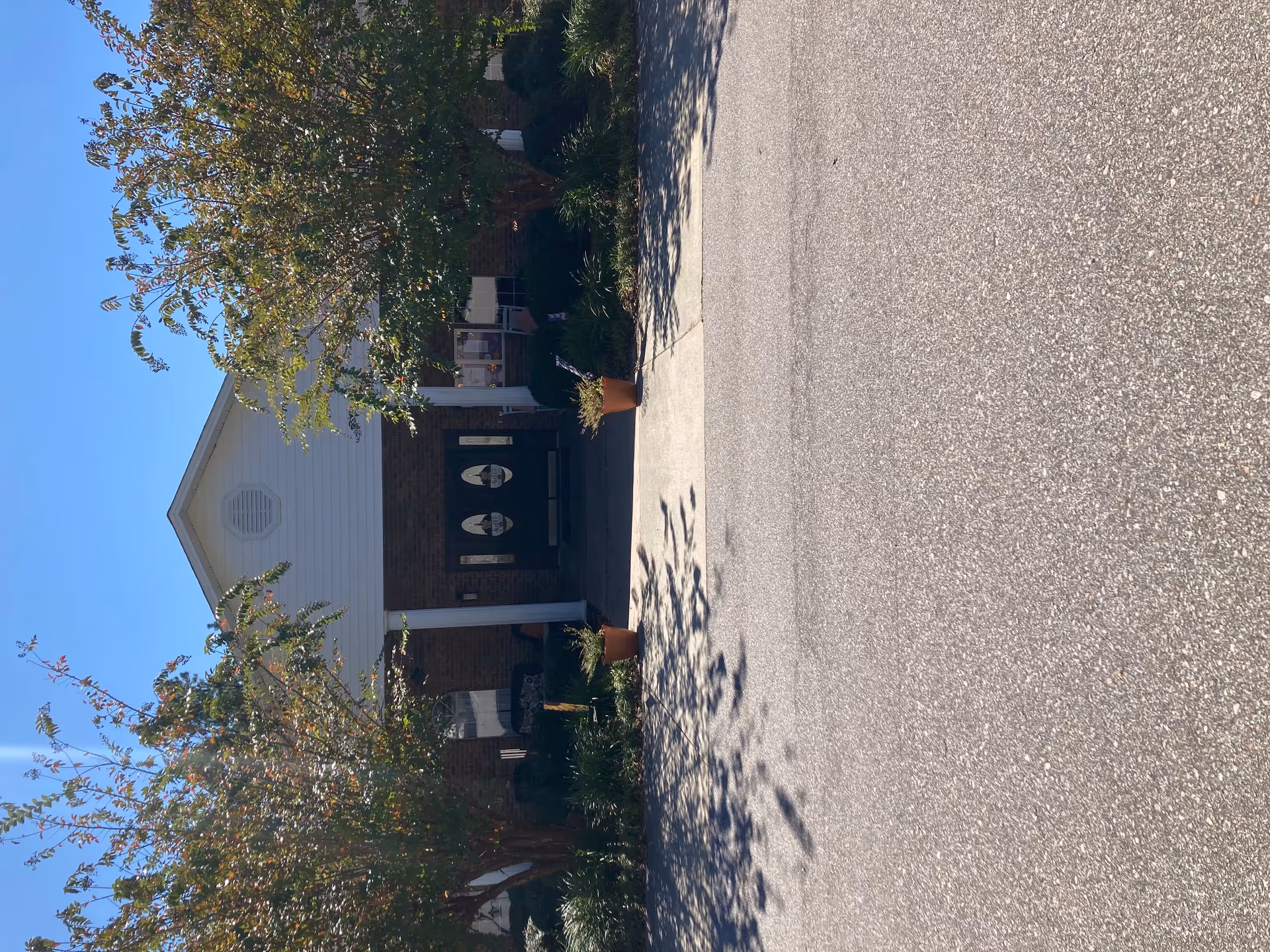 Front entrance of a brick senior living facility with shrubs and trees.