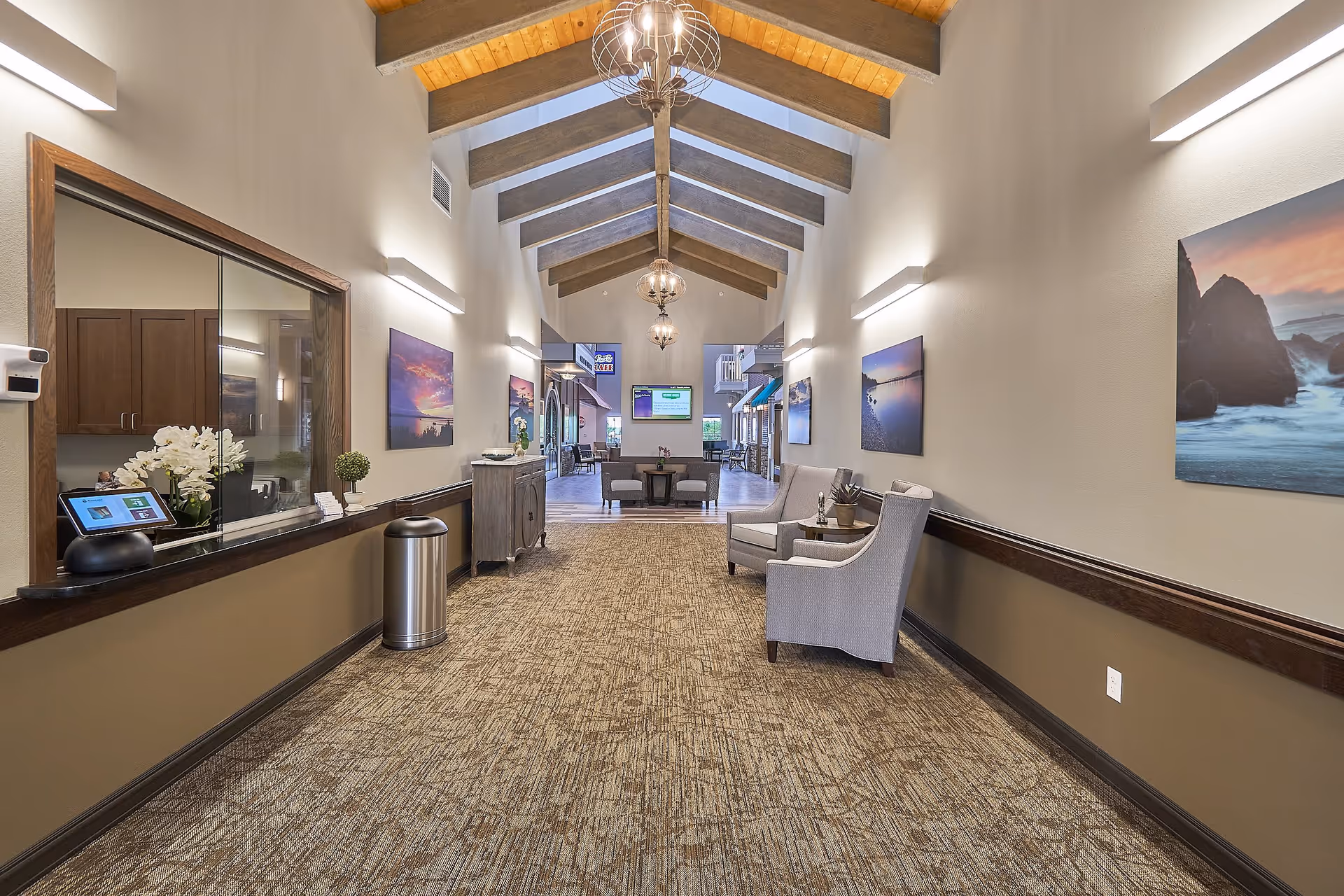 Spacious reception hallway with vaulted wood-beamed ceiling, seating area, reception window and decorative lighting.