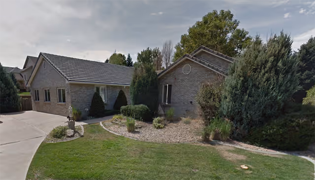 Exterior view of Lansing Assisted Living building with landscaped front yard and driveway.