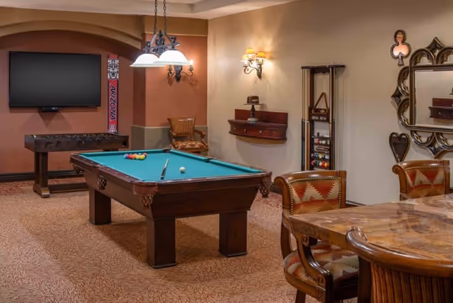 Recreation room with a pool table, wall-mounted TV, foosball table, and seating.