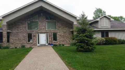 Brick senior living facility front entrance with a path and manicured lawn