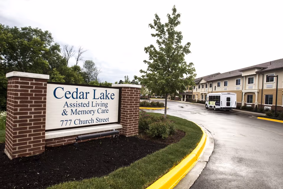 Cedar Lake sign with curved driveway and a building in the background.
