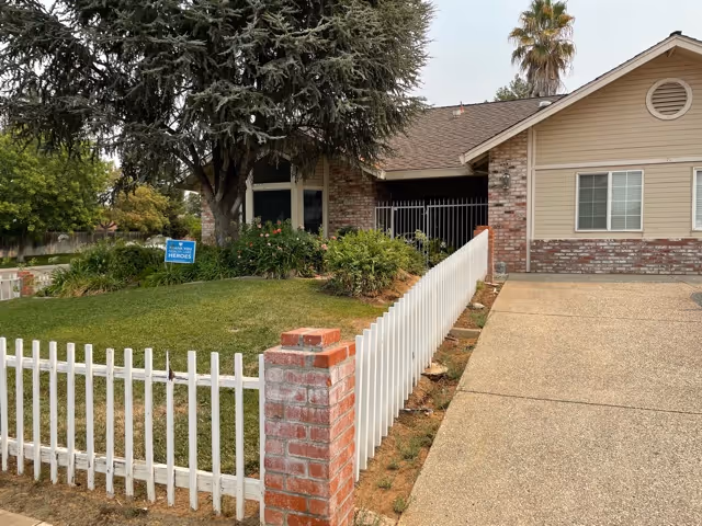 Exterior view of Laguna Park senior facility with a white fence and brick front entrance.