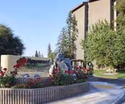 Exterior view of Rosewood Retirement Community entrance with a sign, flowers, and trees.