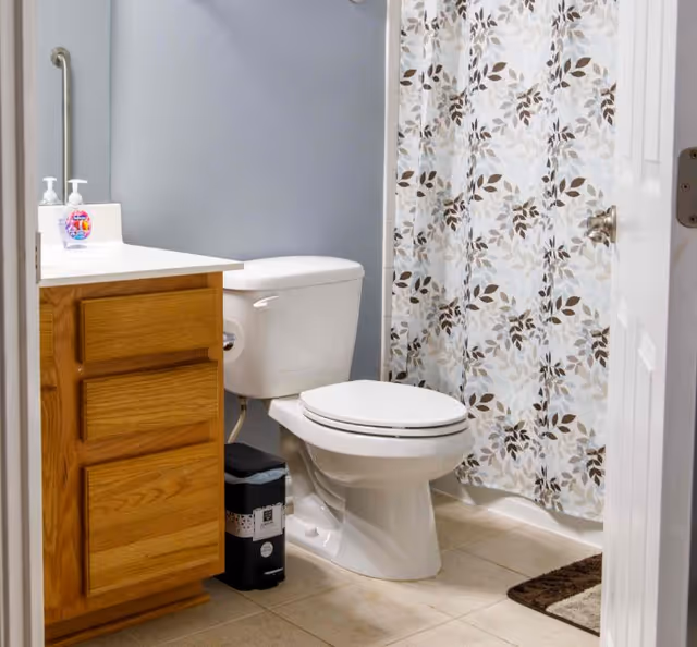 Small bathroom with a toilet, wooden vanity and countertop, and a floral shower curtain.