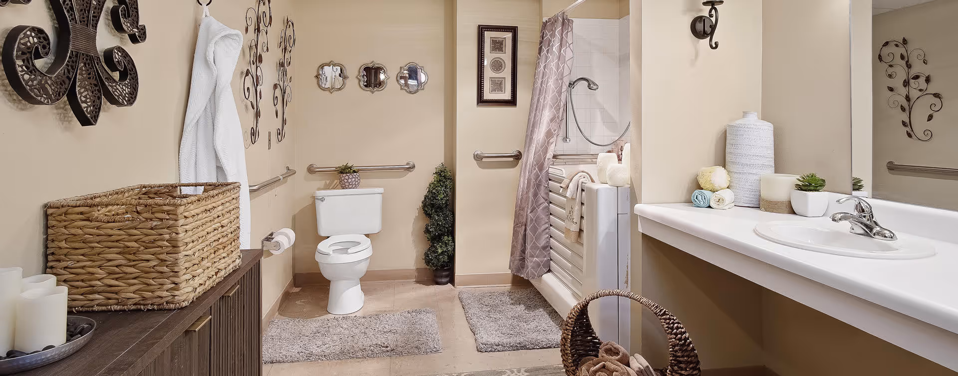 A clean and well-decorated bathroom featuring a toilet, a bathtub with a shower curtain, a sink with a countertop, and various decorative items including wall art, a basket, towels, and candles.