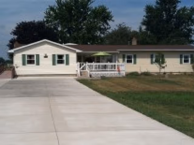 Single-story senior living facility with a front driveway, porch, and green lawn.