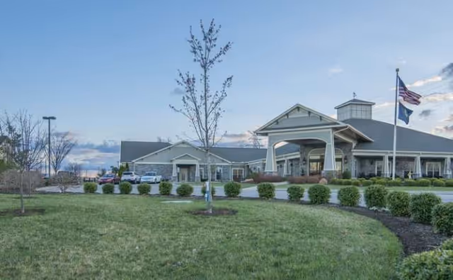 Exterior view of Morning Pointe of Lexington with entrance, manicured lawn, and American flag.