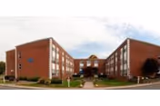Exterior view of a brick senior living facility with twin wings and front lawn.