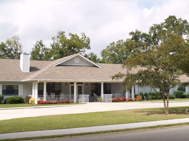 Single-story senior living facility with a covered porch, columns, and landscaped front yard.