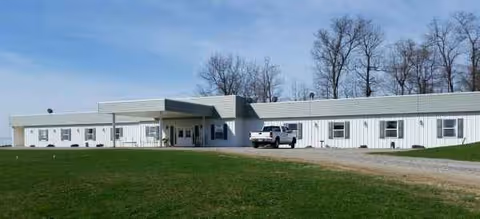 Front view of Country Manor Personal Care Home, a white single-story facility with driveway.