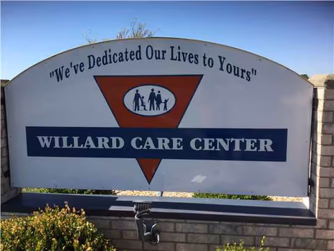Outdoor front sign for Willard Care Center with triangle logo and slogan.