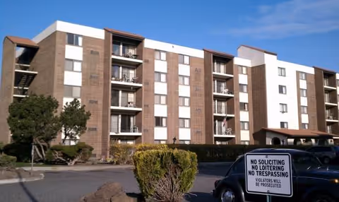 A multi-story Desert Villa senior living building with a parking lot and no trespassing sign.