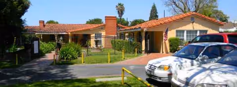 Exterior view of The Villa Senior Home: single-story building with red-tile roof and parked car.