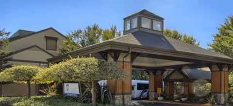 Exterior view of Brookdale Paulin Creek facility with a covered entrance and parked vehicles.