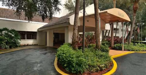 Exterior of a senior living facility with a covered entrance and landscaped driveway.