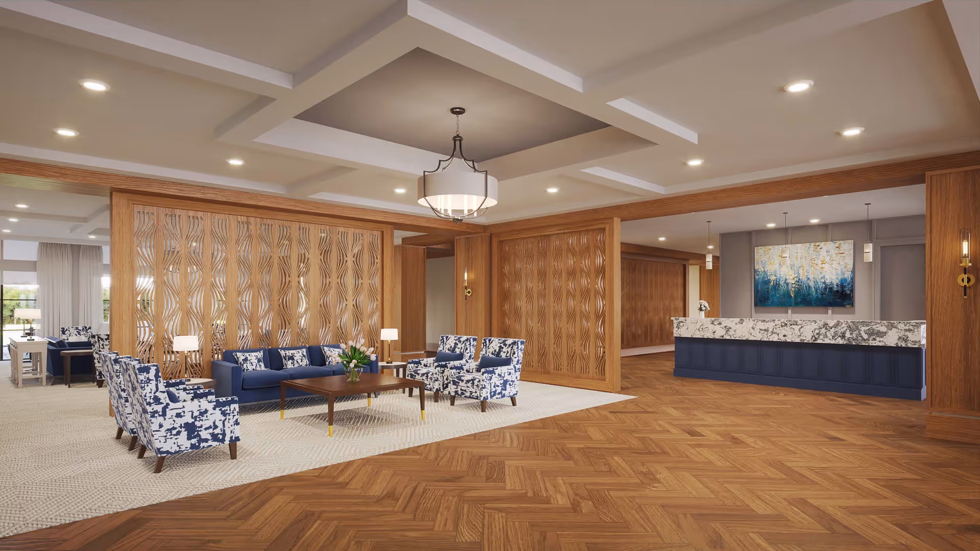 A spacious and elegant interior common area featuring a seating arrangement with blue and white patterned armchairs and a blue sofa around a wooden coffee table. The area is partially separated by decorative wooden panels. To the right, there is a reception desk with a marble countertop and a large abstract painting on the wall behind it. The floor is a combination of wood and carpet, and the ceiling has recessed lighting and a central chandelier.