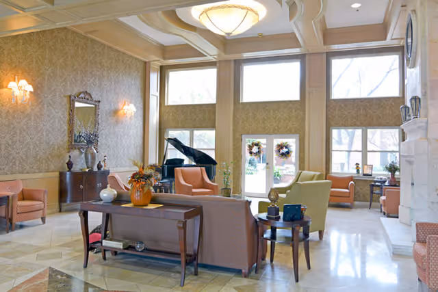 Elegantly furnished lobby with sofas, armchairs, a grand piano, and large windows letting in natural light.