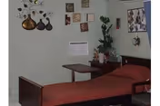 A small hospital-style bedroom with a metal bed, red cover, and wall decor.