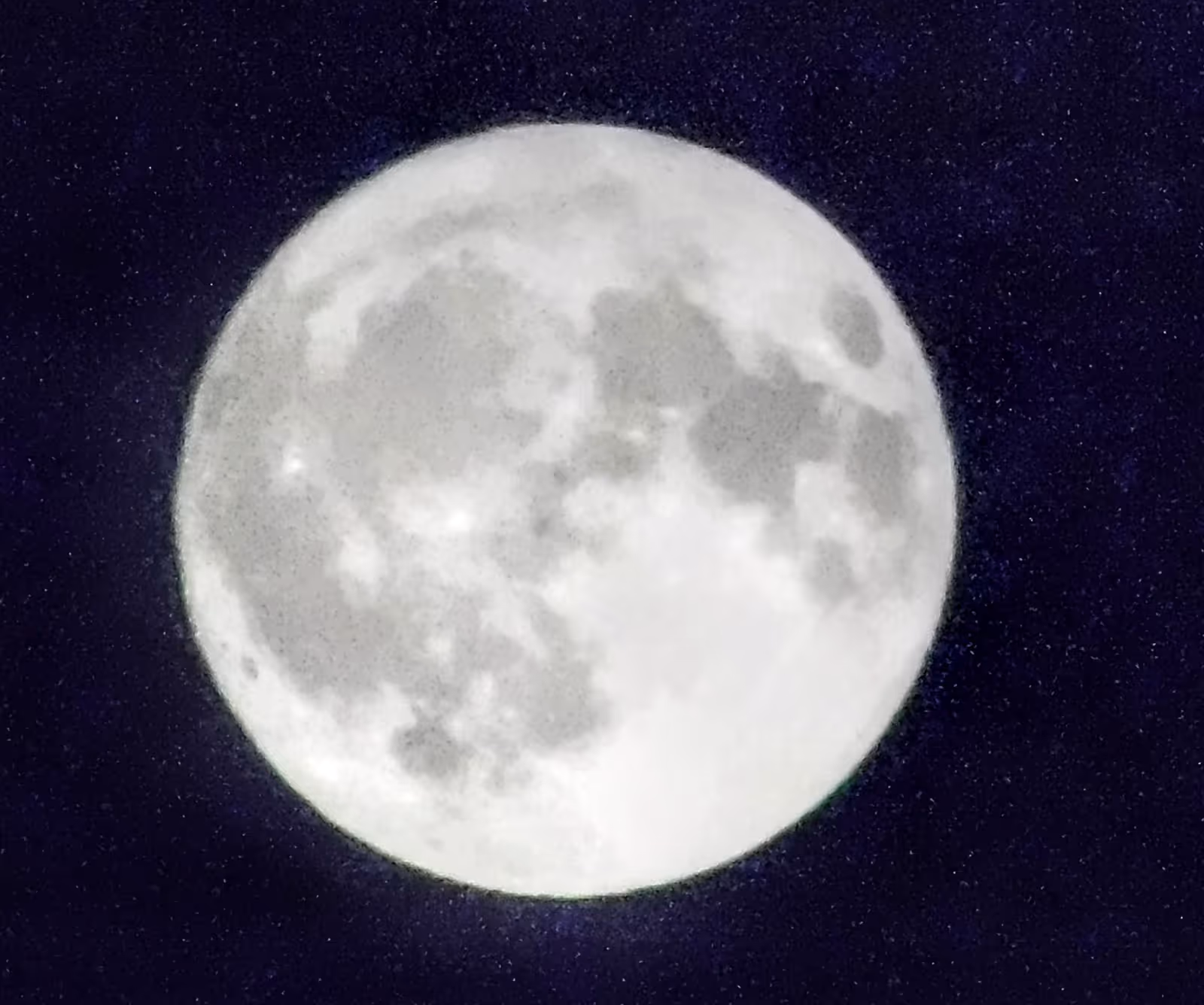 Close-up of a full moon against a dark, starry night sky.
