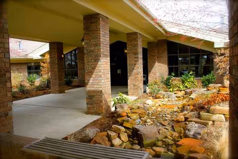 Brick columns support a covered entrance with glass windows and rock landscaping.
