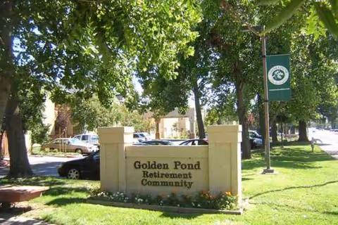 Front entrance of Golden Pond Retirement Community with a stone sign and trees.