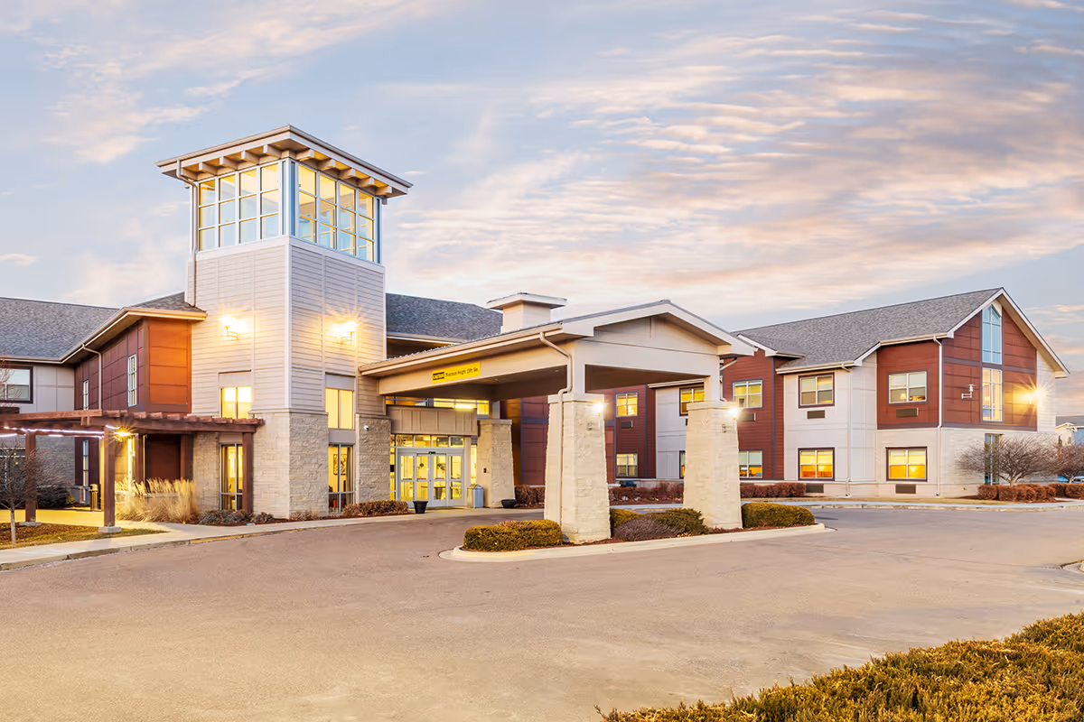 Exterior view of Coal Creek Post Acute & Assisted Living, showing the entrance canopy, a tall tower, and a curved driveway.