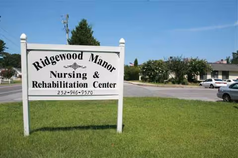 Sign for Ridgewood Manor Nursing & Rehabilitation Center on a grassy lawn with building behind.