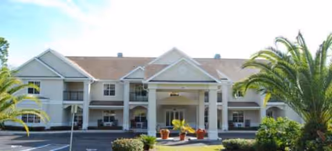 A senior living facility with a covered entrance, two-story building facade, and palm trees.