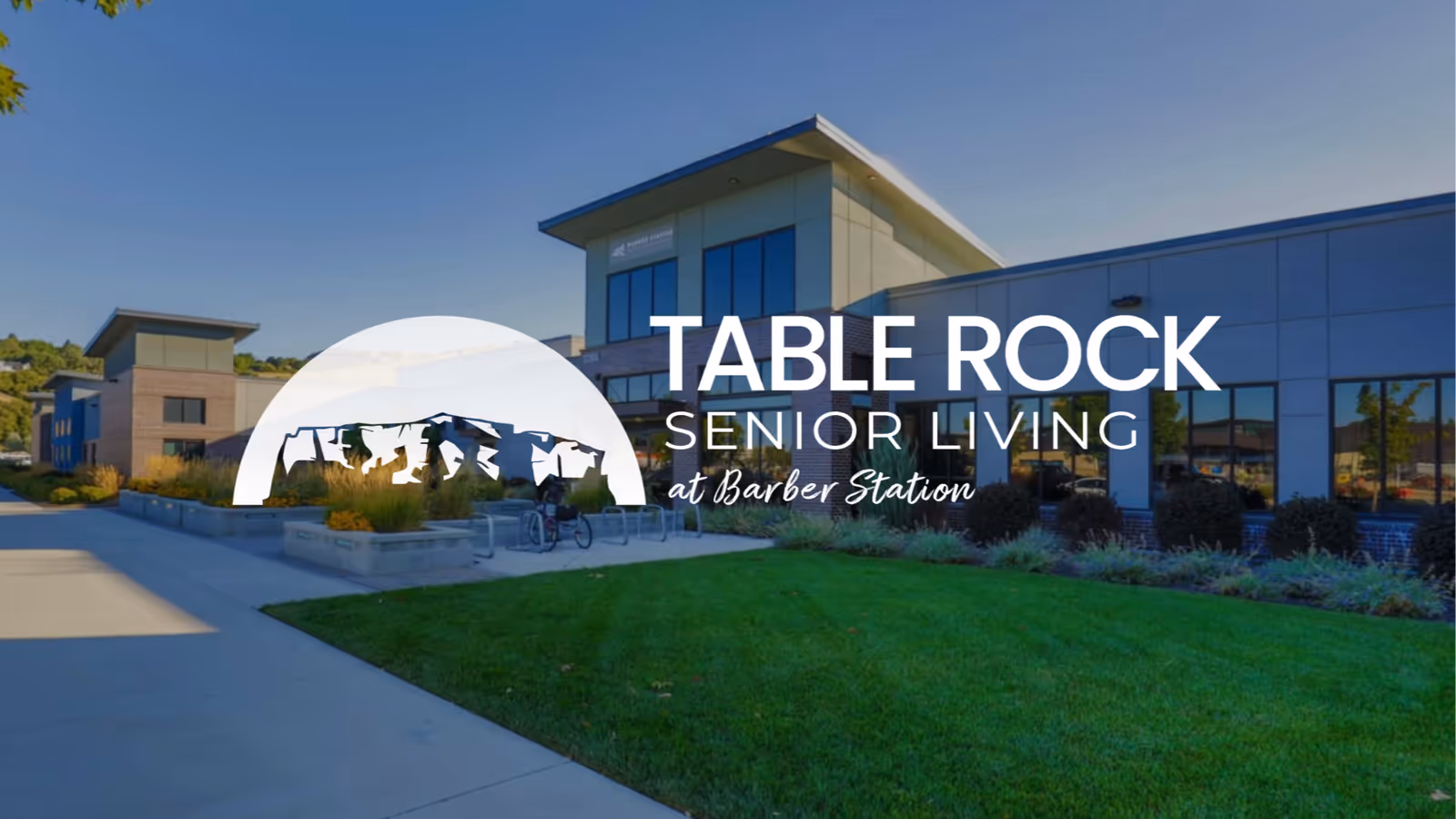 Exterior view of Table Rock Senior Living at Barber Station facility with modern buildings, green lawn, and clear blue sky.