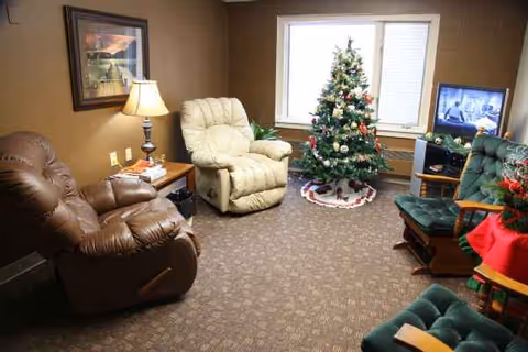 Cozy senior living lounge with recliners, a Christmas tree, and a television.