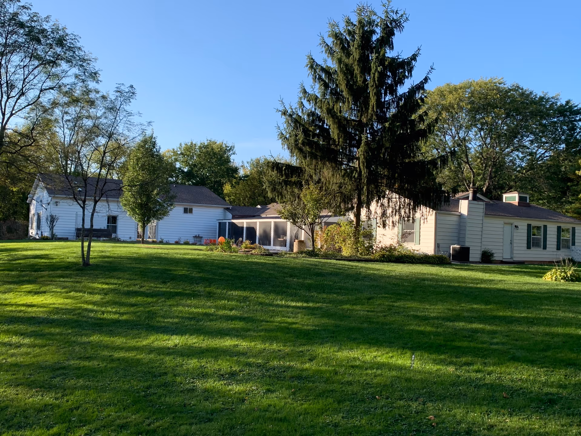 A wide view shows The Heathers Ringwood outdoor grounds with white buildings and green lawn.